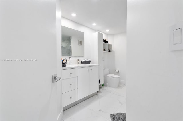 bathroom featuring vanity, a shower with shower door, and toilet