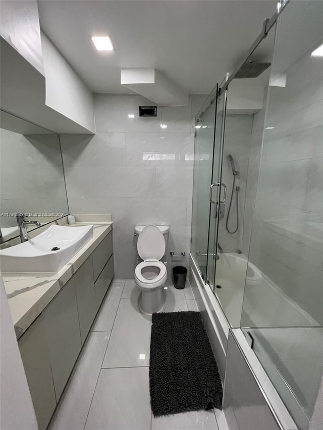 bathroom featuring toilet, an enclosed shower, tile walls, vanity, and tile patterned flooring