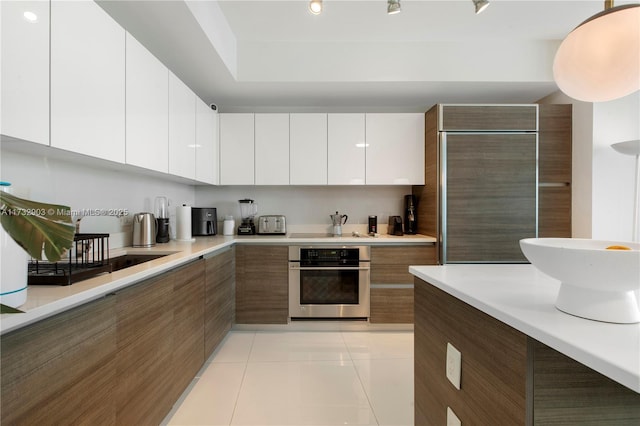 kitchen with white cabinetry, stainless steel oven, paneled fridge, and light tile patterned floors