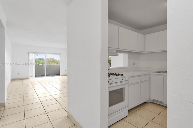 kitchen with ventilation hood, white cabinetry, white gas range, and light tile patterned flooring