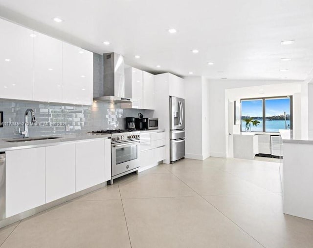 kitchen featuring appliances with stainless steel finishes, sink, white cabinets, decorative backsplash, and wall chimney exhaust hood