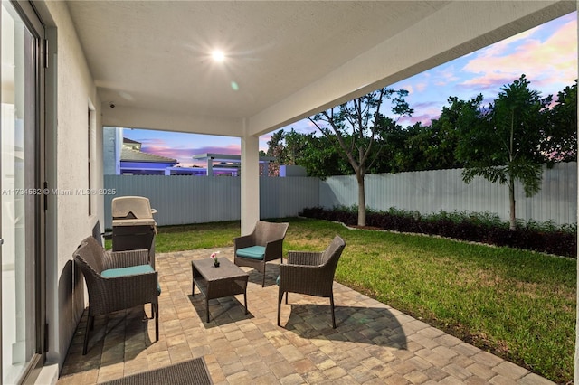 patio terrace at dusk featuring a yard