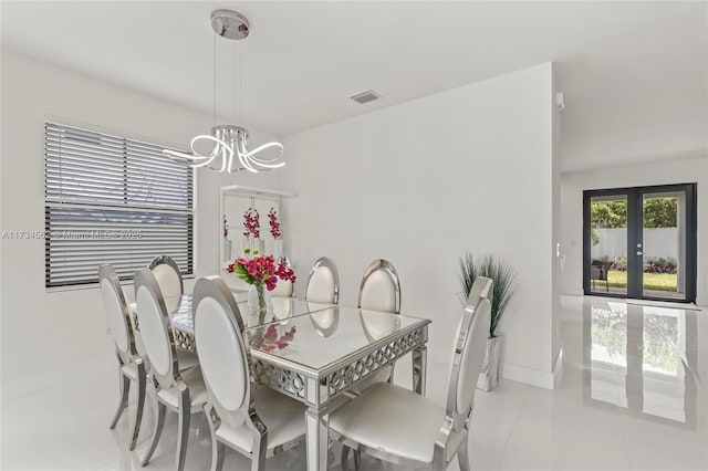 dining room with an inviting chandelier, light tile patterned floors, and french doors