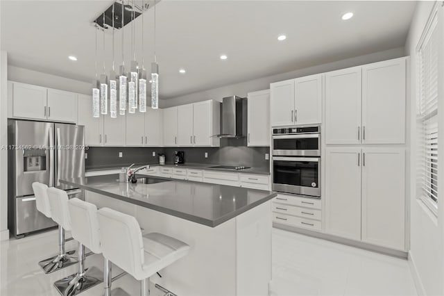 kitchen featuring wall chimney range hood, stainless steel appliances, sink, and white cabinets