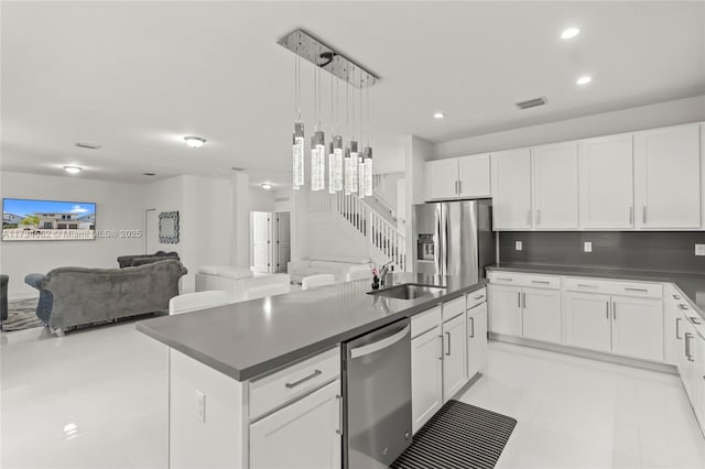 kitchen featuring a kitchen island, appliances with stainless steel finishes, pendant lighting, white cabinetry, and sink