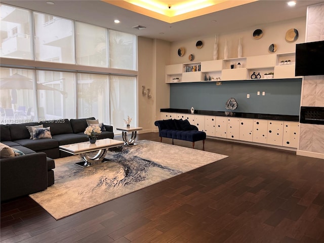 living room with a towering ceiling, dark wood-type flooring, and expansive windows