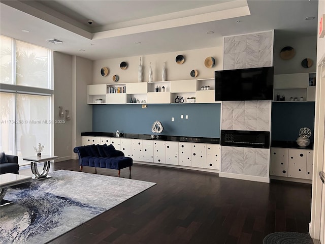 living room with a tray ceiling and dark hardwood / wood-style floors