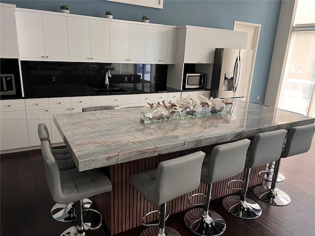 kitchen featuring white cabinetry, appliances with stainless steel finishes, sink, and a breakfast bar area