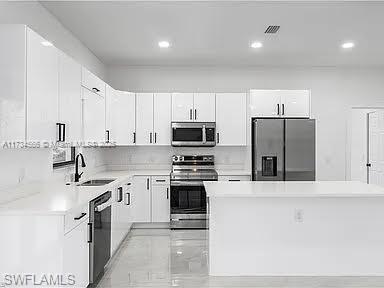 kitchen featuring appliances with stainless steel finishes, sink, and white cabinets