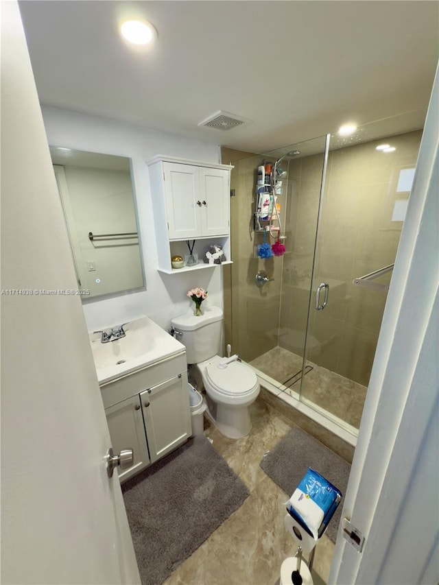 bathroom featuring vanity, a shower with shower door, and toilet