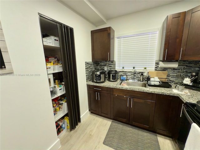 kitchen featuring sink, backsplash, electric range, light stone counters, and light wood-type flooring