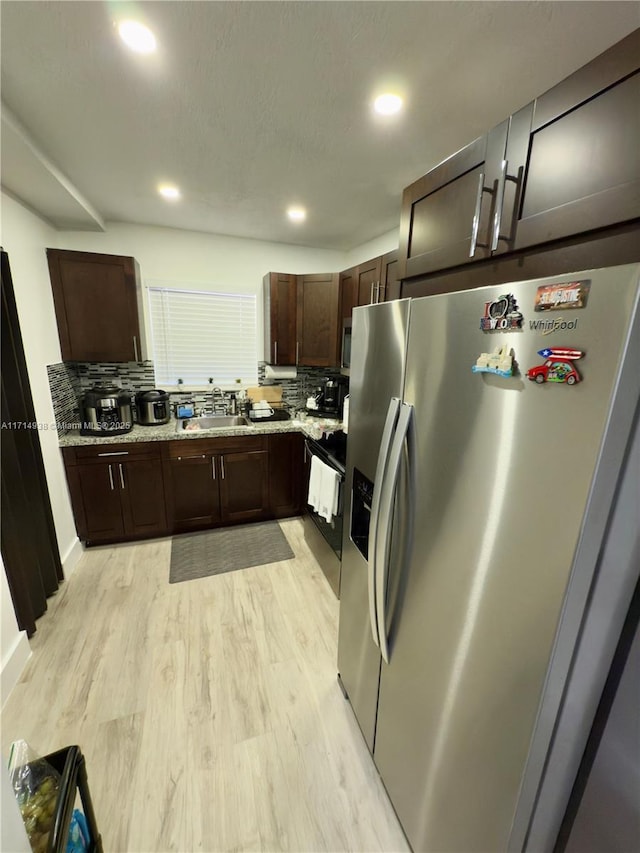 kitchen with sink, tasteful backsplash, dark brown cabinets, appliances with stainless steel finishes, and light hardwood / wood-style floors