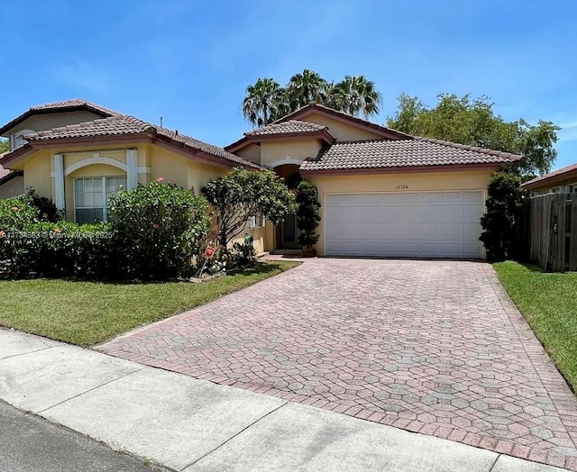 mediterranean / spanish home featuring a garage and a front lawn