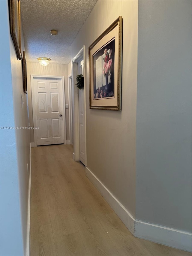 hall featuring light hardwood / wood-style flooring and a textured ceiling