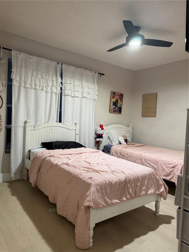 bedroom featuring ceiling fan, light hardwood / wood-style flooring, and a textured ceiling