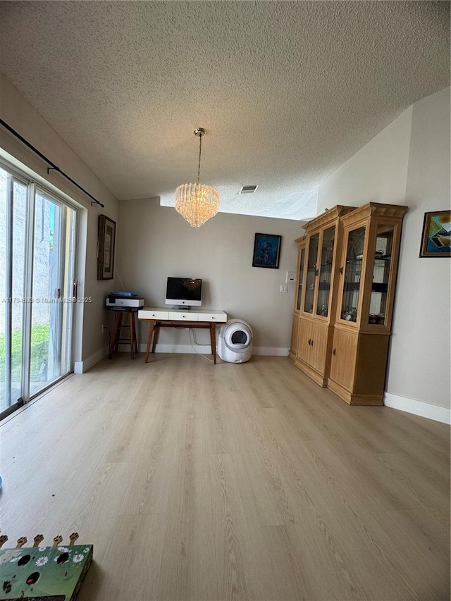 interior space featuring a notable chandelier, a textured ceiling, and light hardwood / wood-style flooring