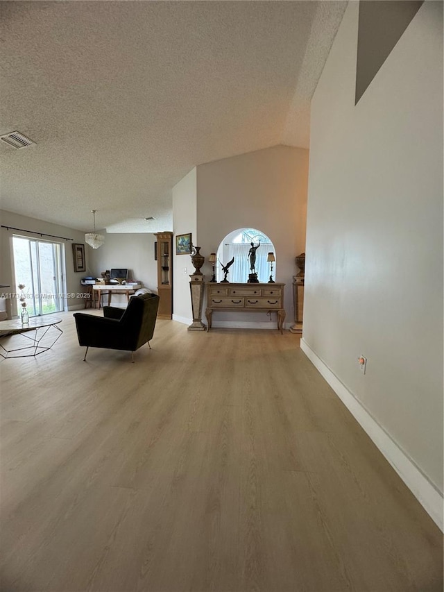 living room featuring lofted ceiling, a textured ceiling, and light wood-type flooring