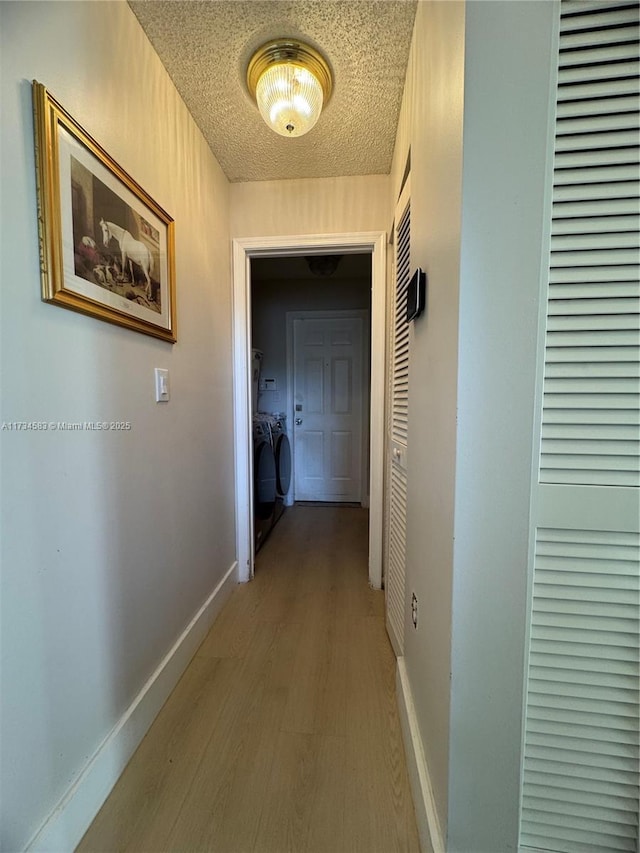 corridor featuring a textured ceiling, wood-type flooring, and washing machine and clothes dryer