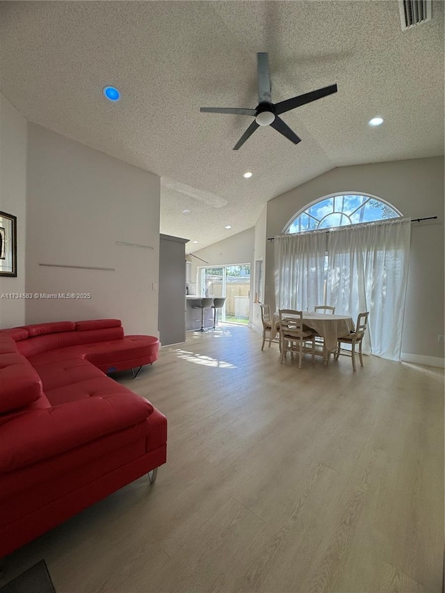 living room with ceiling fan, lofted ceiling, hardwood / wood-style floors, and a textured ceiling