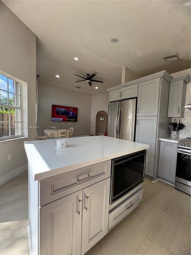 kitchen featuring gray cabinetry, a kitchen island, light hardwood / wood-style floors, and appliances with stainless steel finishes