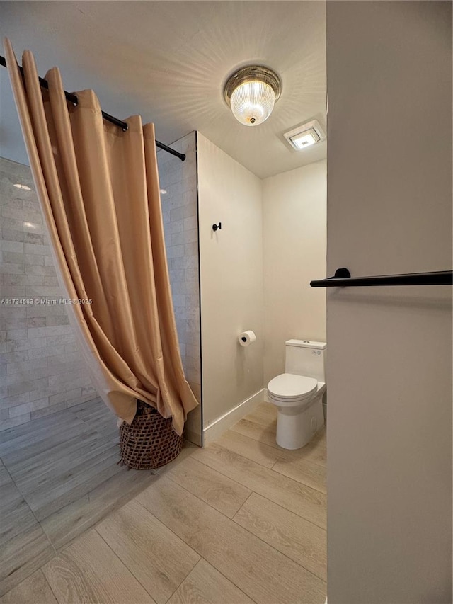 bathroom featuring walk in shower, wood-type flooring, and toilet