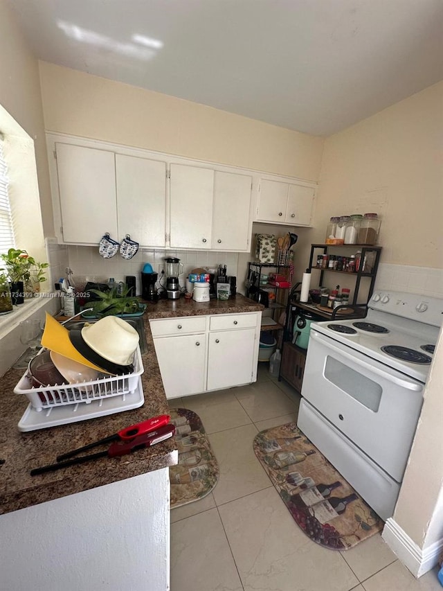 kitchen with white cabinets, light tile patterned floors, and electric range