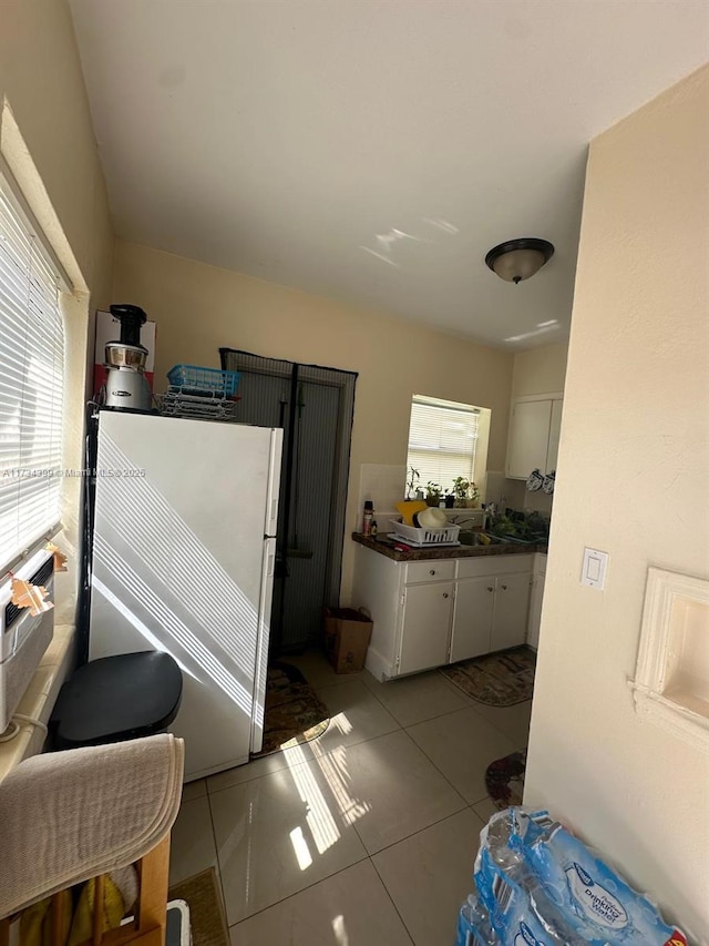 kitchen with white cabinetry, light tile patterned floors, and fridge