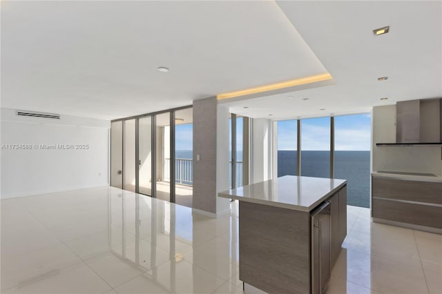 kitchen with a healthy amount of sunlight, a kitchen island, a wall of windows, and a water view