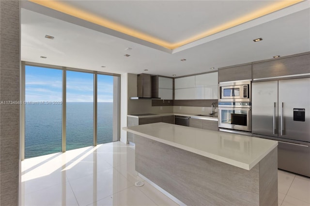 kitchen with light tile patterned floors, sink, a water view, built in appliances, and white cabinets