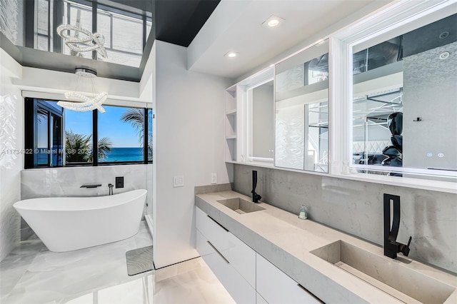 bathroom with a healthy amount of sunlight, vanity, a chandelier, and a washtub