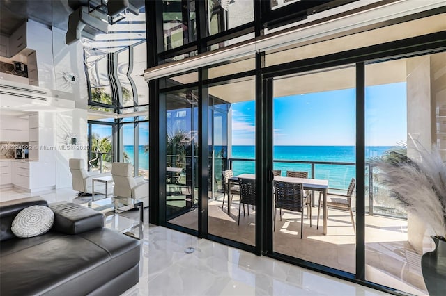 entryway featuring a water view, a beach view, and a wall of windows