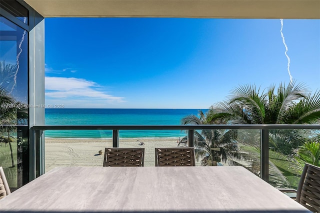 balcony featuring a view of the beach and a water view