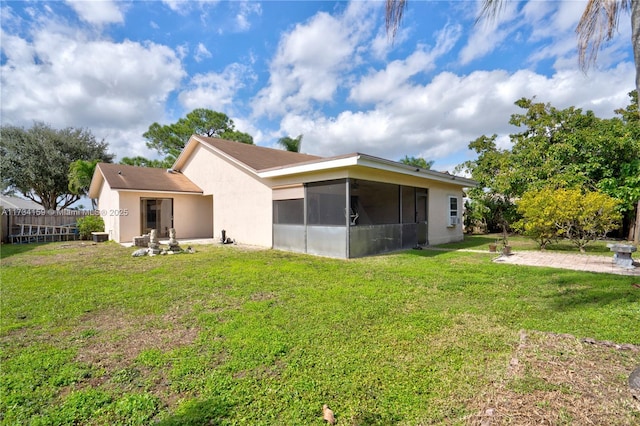 rear view of property featuring a sunroom, a patio area, and a lawn