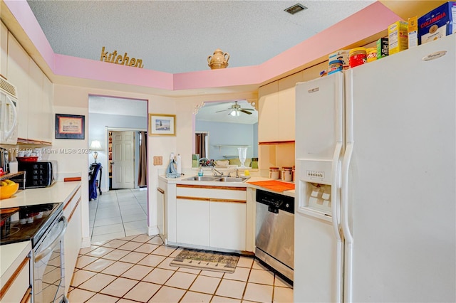 kitchen featuring light tile patterned flooring, white cabinetry, a textured ceiling, ceiling fan, and stainless steel appliances