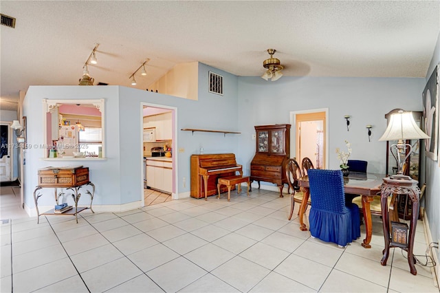 tiled dining area featuring lofted ceiling, ceiling fan, and a textured ceiling