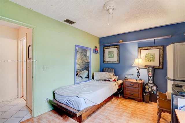 bedroom with light tile patterned flooring, ceiling fan, and a textured ceiling