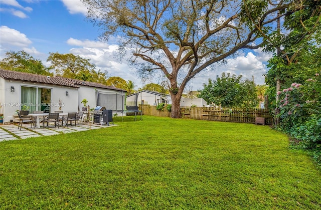 view of yard with a trampoline and a patio area