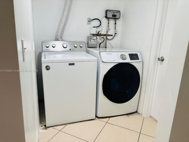 clothes washing area featuring washing machine and clothes dryer and light tile patterned floors