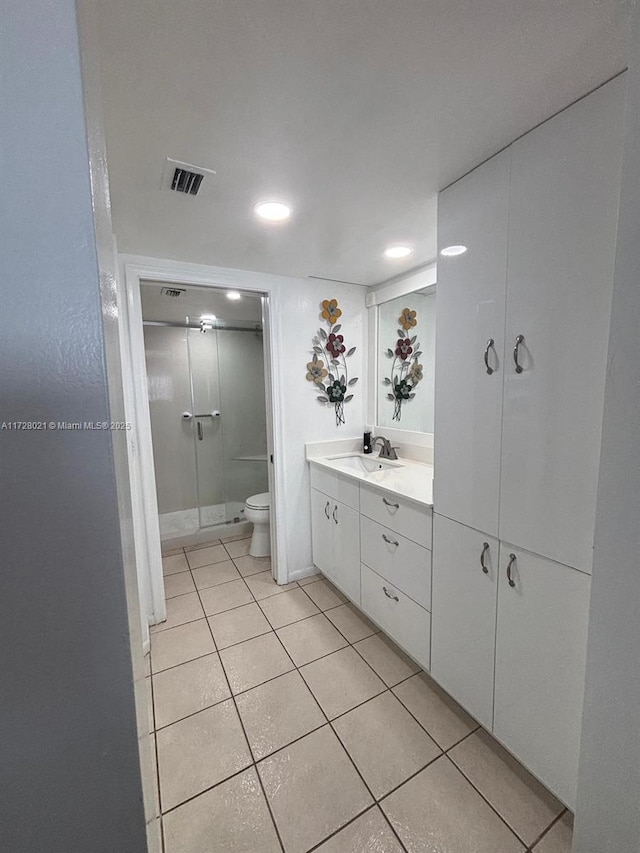 bathroom with vanity, toilet, a shower with shower door, and tile patterned flooring