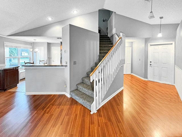 stairway featuring hardwood / wood-style flooring, lofted ceiling, and a textured ceiling