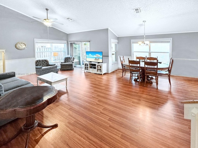 living room with lofted ceiling, crown molding, a textured ceiling, light hardwood / wood-style floors, and ceiling fan with notable chandelier