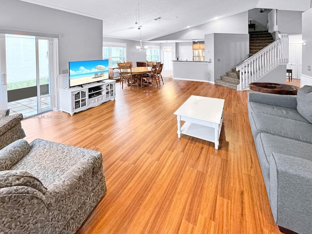 living room with lofted ceiling, an inviting chandelier, a textured ceiling, and light hardwood / wood-style flooring