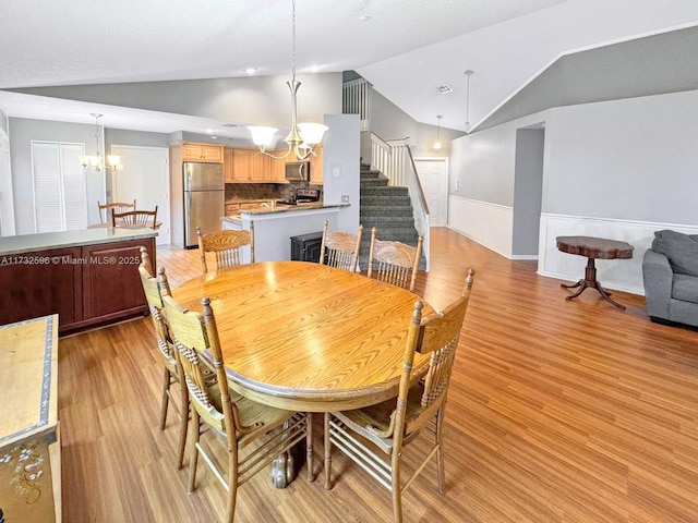 dining area featuring an inviting chandelier, light hardwood / wood-style floors, and vaulted ceiling