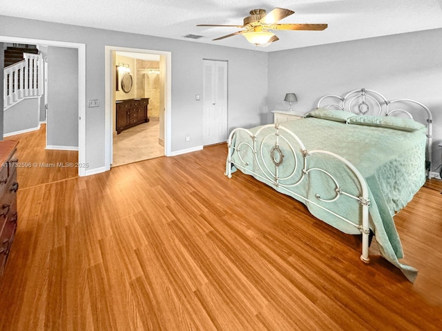 bedroom with ceiling fan, ensuite bathroom, wood-type flooring, and a textured ceiling