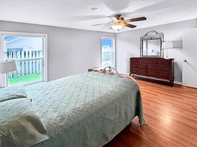 bedroom featuring ceiling fan, light hardwood / wood-style floors, and a textured ceiling