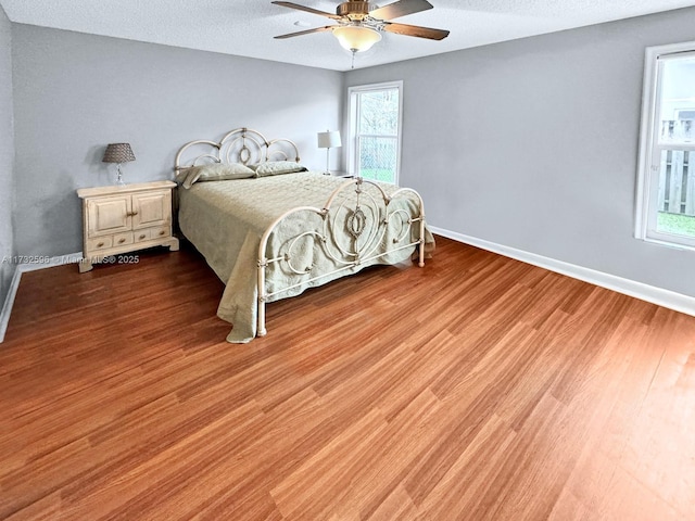 bedroom with ceiling fan, light hardwood / wood-style floors, and a textured ceiling