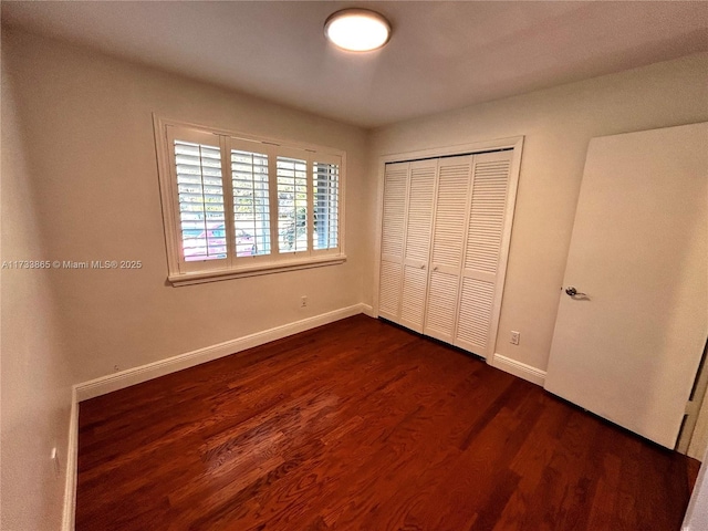 unfurnished bedroom with dark wood-type flooring and a closet