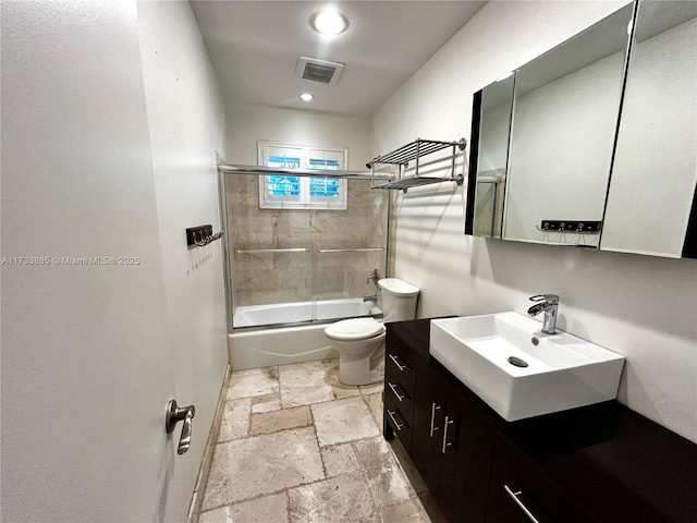 full bathroom featuring toilet, vanity, and shower / bath combination with glass door