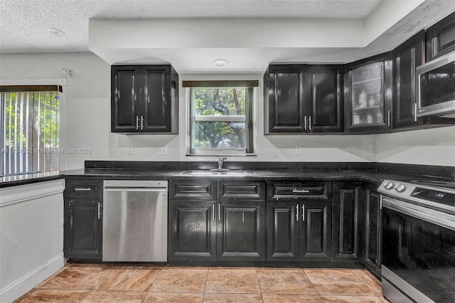 kitchen featuring sink, light tile patterned floors, a textured ceiling, and appliances with stainless steel finishes