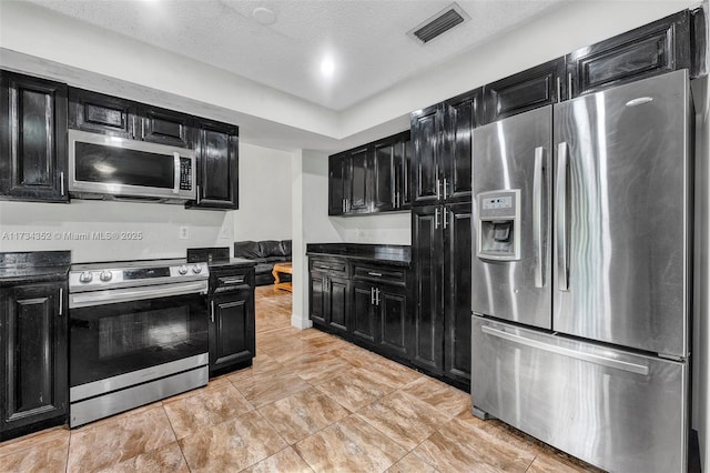 kitchen with light tile patterned flooring, stainless steel appliances, and a textured ceiling